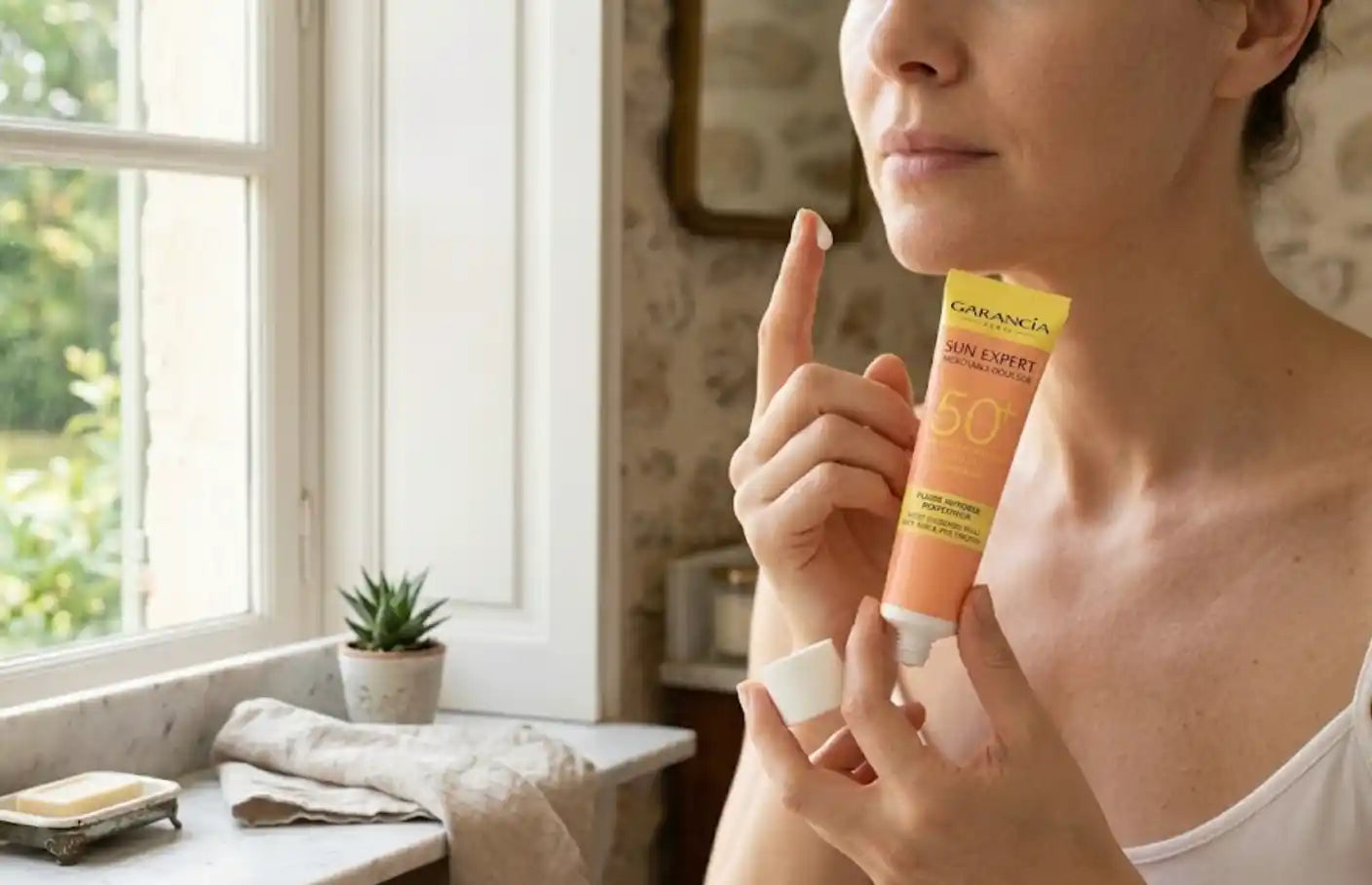 Femme appliquant de la crème solaire Garancia Sun Expert SPF 50+.